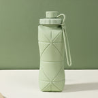 Green silicone folding bottle with packaging on a green background