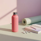 Pink water bottle with silver cap on a light surface with a neutral background