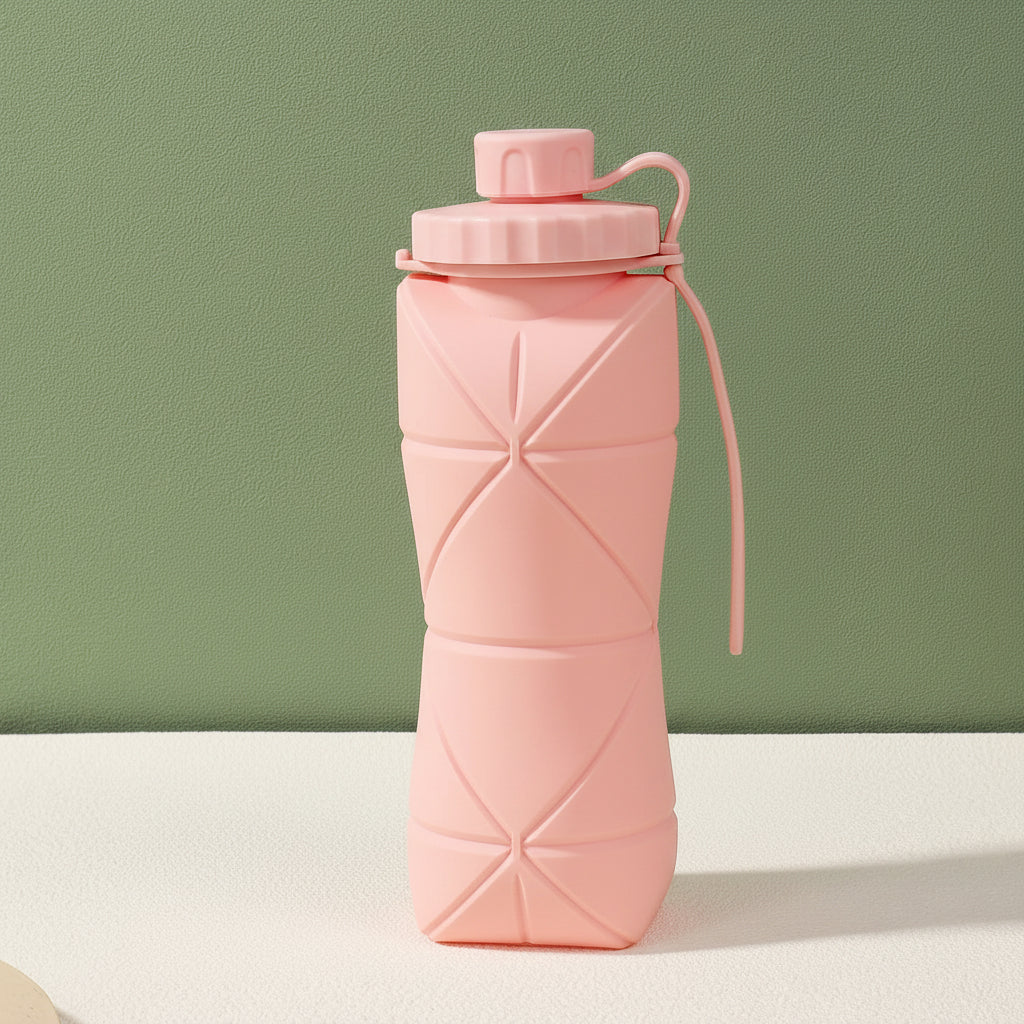 Pink silicone folding bottle with packaging on a light surface and green background