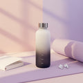 Gradient water bottle with measurement markings on a light surface.
