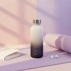 Gradient water bottle with measurement markings on a light surface.
