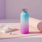 Gradient blue to pink water bottle with measurement markings on a light surface.