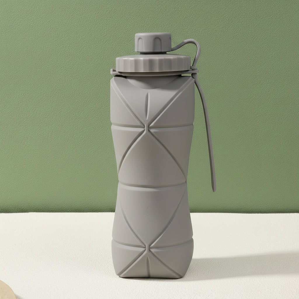 Gray silicone folding bottle with packaging on a light surface and green background