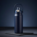 Dark blue water bottle with a black lid on a dark background